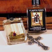 Bottle of conjure oil and a cross on a wooden surface